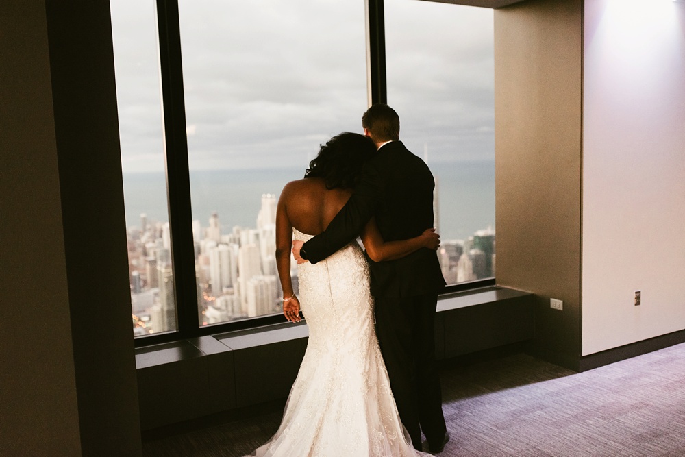 bride and groom hugging in front of window at skydeck willis tower wedding