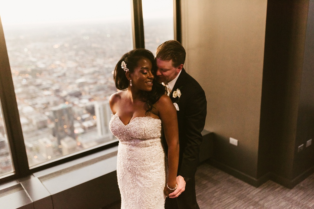 bride and groom smiling in front of window at skydeck willis tower wedding