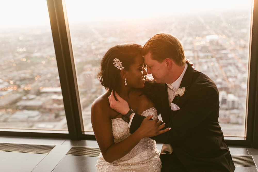 bride and groom hugging in front of window at sunset at skydeck willis tower wedding