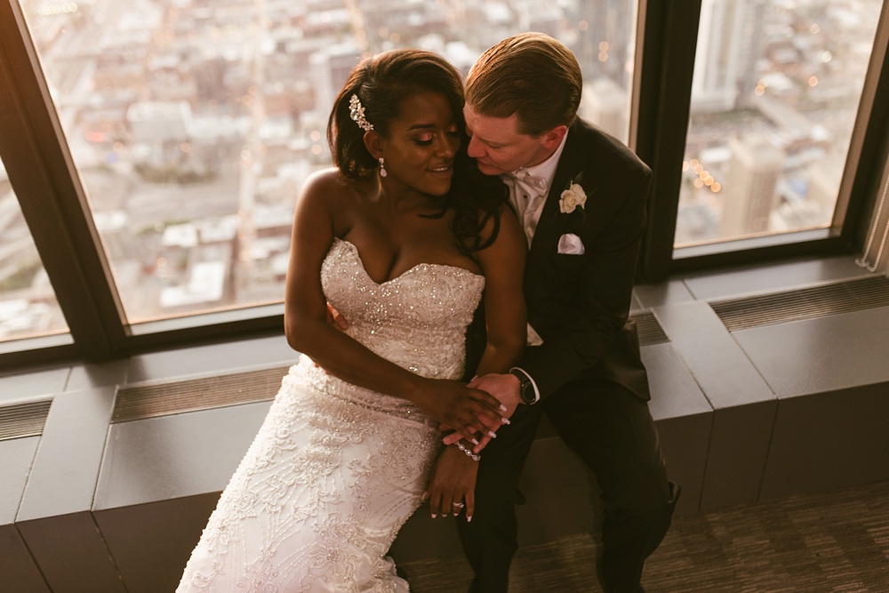 bride and groom hugging in front of window at sunset at skydeck willis tower wedding