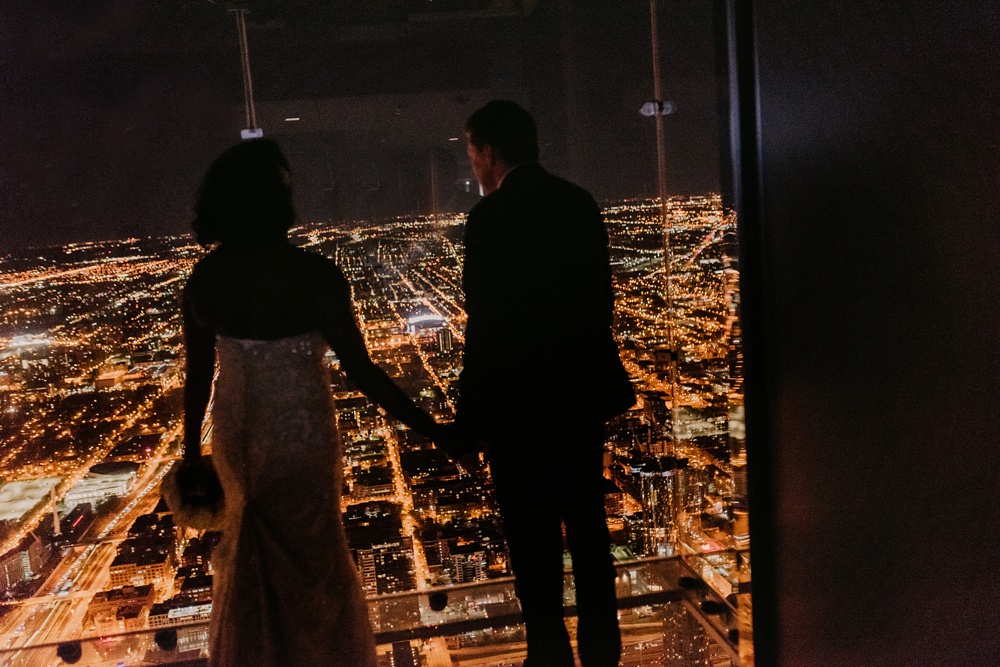 Chicago bride and groom kissing with Chicago downtown skyline at night from willis tower.
