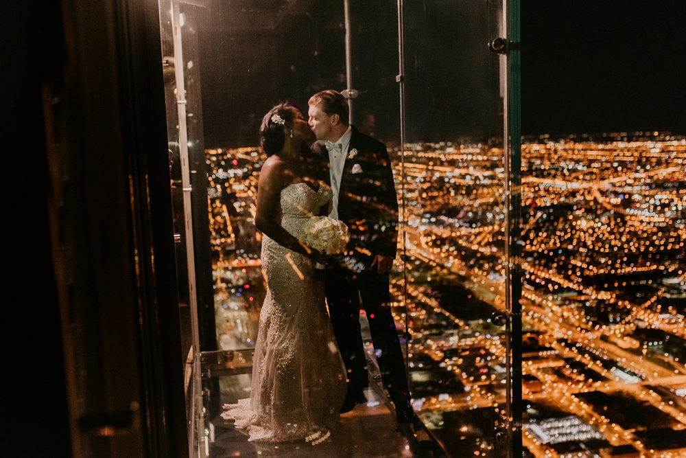 Chicago bride and groom kissing with Chicago downtown skyline at night from willis tower.