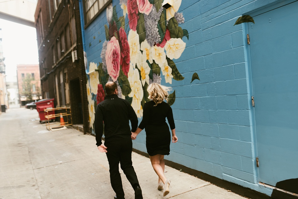 couple holding hands next to mural at downtown fort wayne engagement session