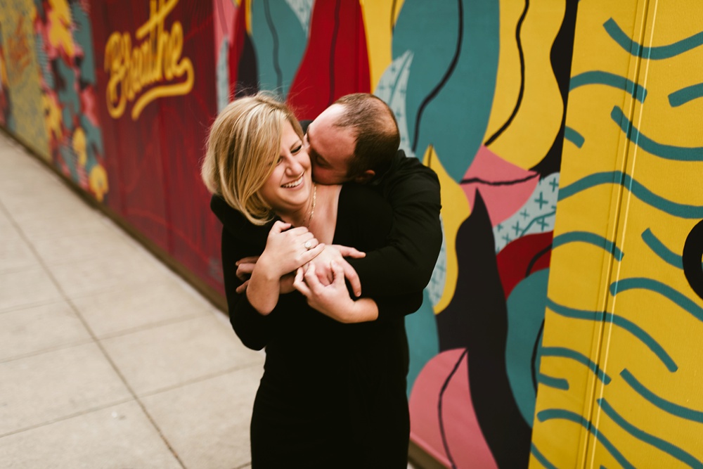 couple kissing next to mural at downtown fort wayne engagement session