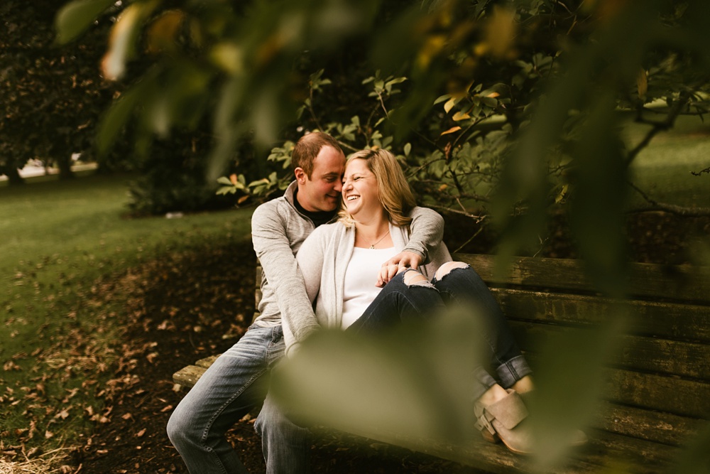 couple laying and laughing in grass at downtown fort wayne engagement session
