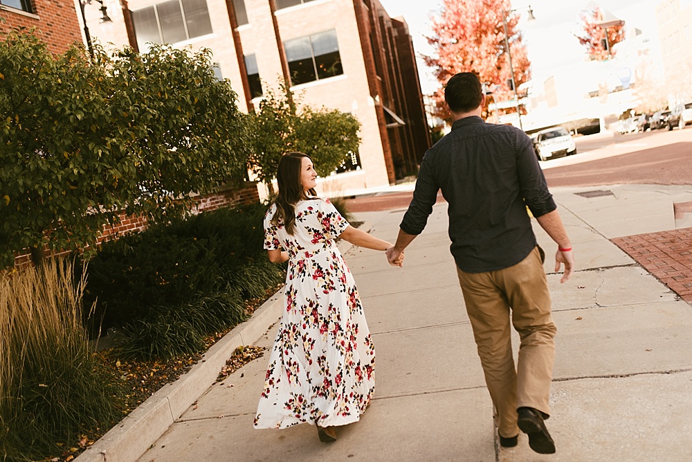 couple holding hands and walking at downtown grand rapids engagement session