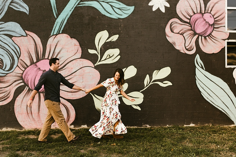 couple holding hands next to mural at downtown grand rapids engagement session