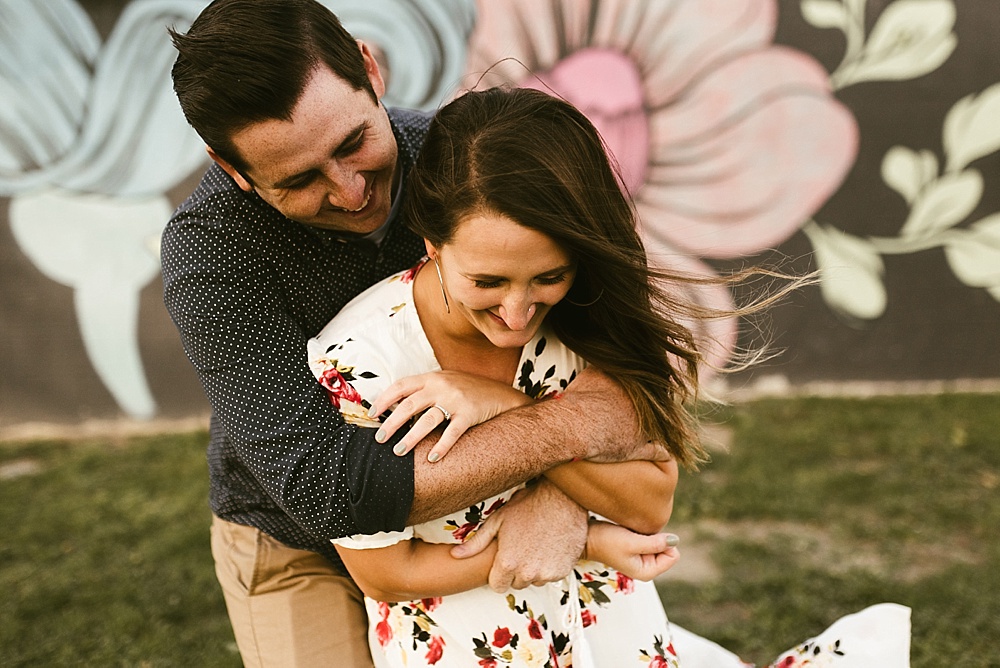 couple hugging next to mural at downtown grand rapids engagement session