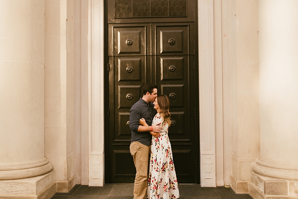 couple hugging in front of door at downtown grand rapids engagement session