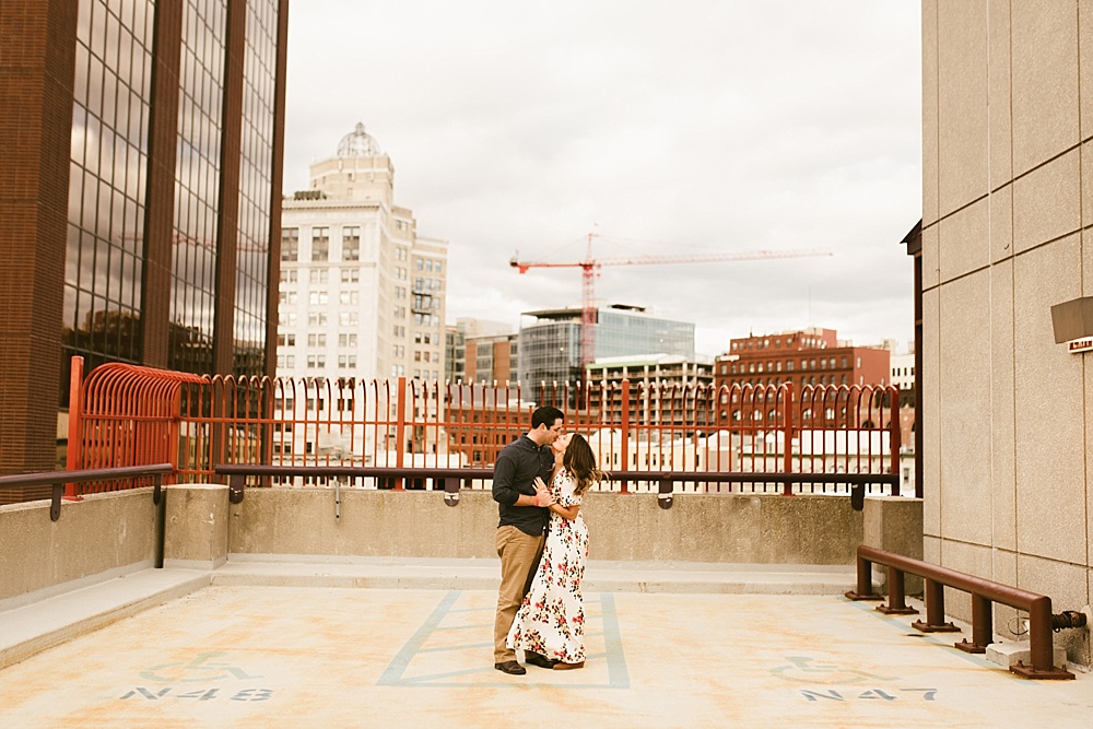 couple hugging next to skyline at downtown grand rapids engagement session
