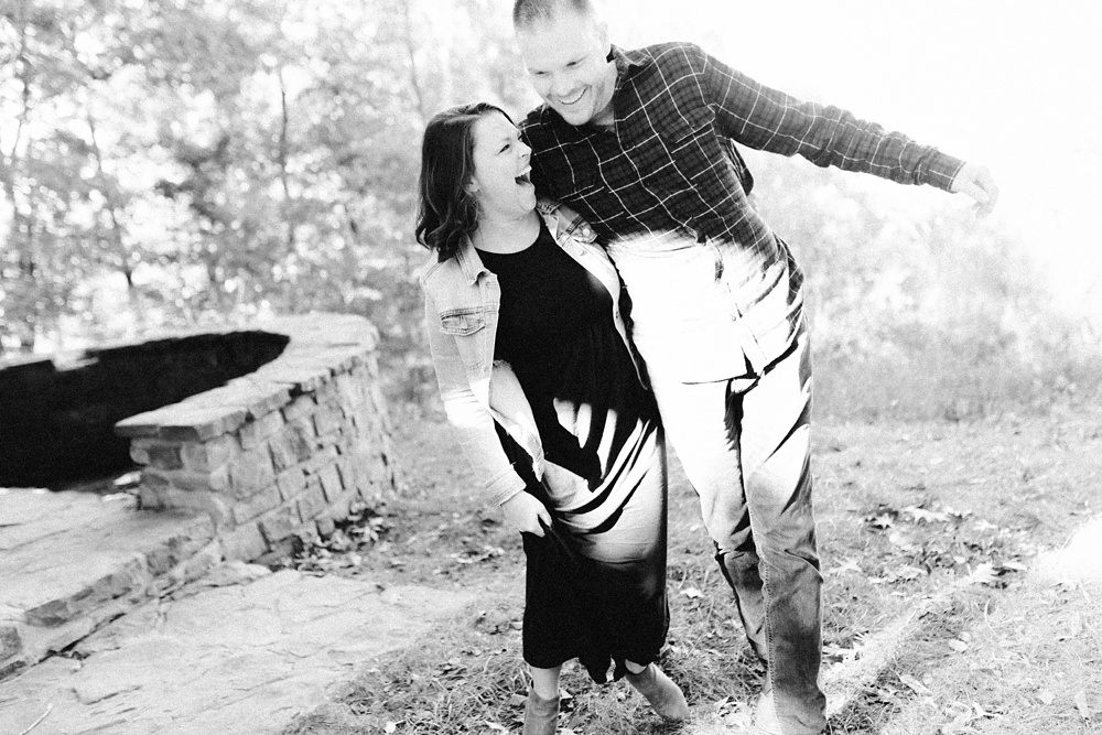 couple laughing next to firepit at brown county engagement session