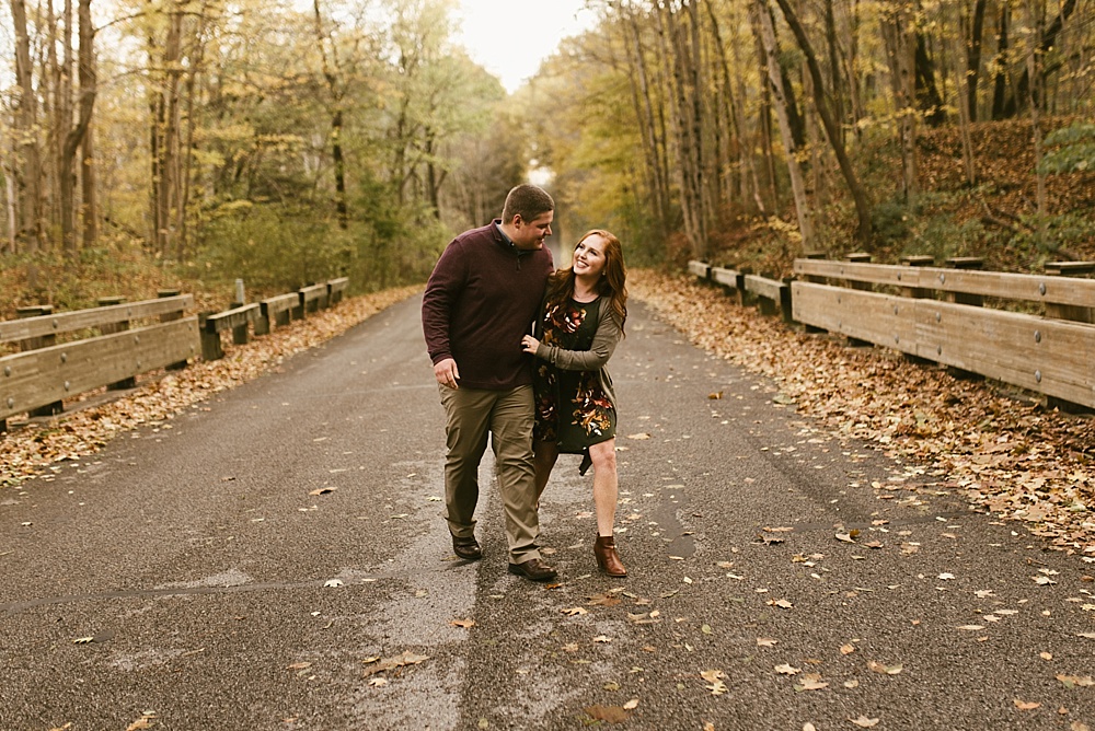 couple laughing on road at chain o'lakes fall engagement session