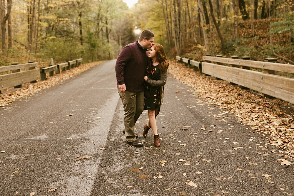 couple holding hands on road at chain o'lakes fall engagement session