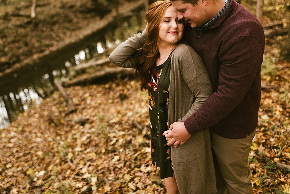 couple hugging in woods at chain o'lakes fall engagement session