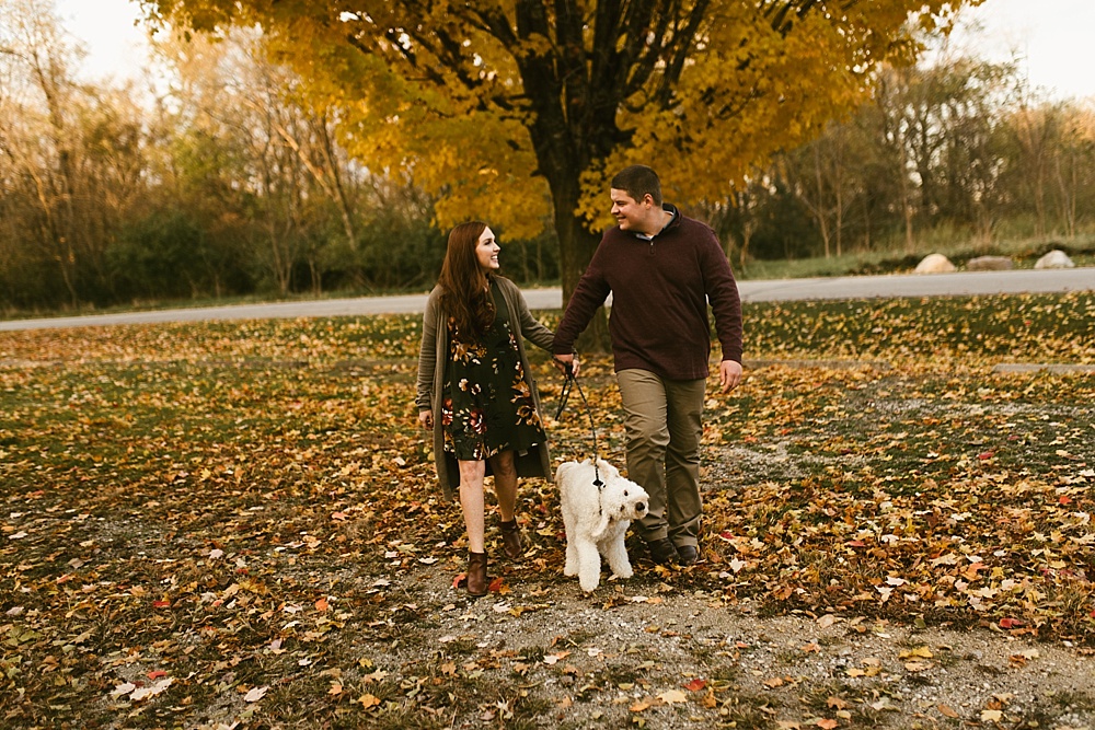 couple walking with dog at chain o'lakes fall engagement session