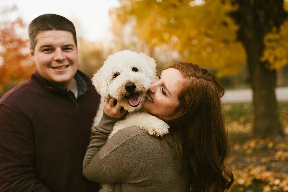 couple kissing dog at chain o'lakes fall engagement session