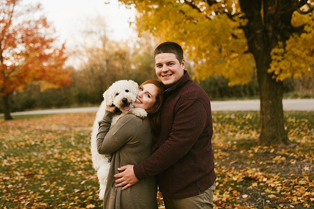 couple holding dog at chain o'lakes fall engagement session
