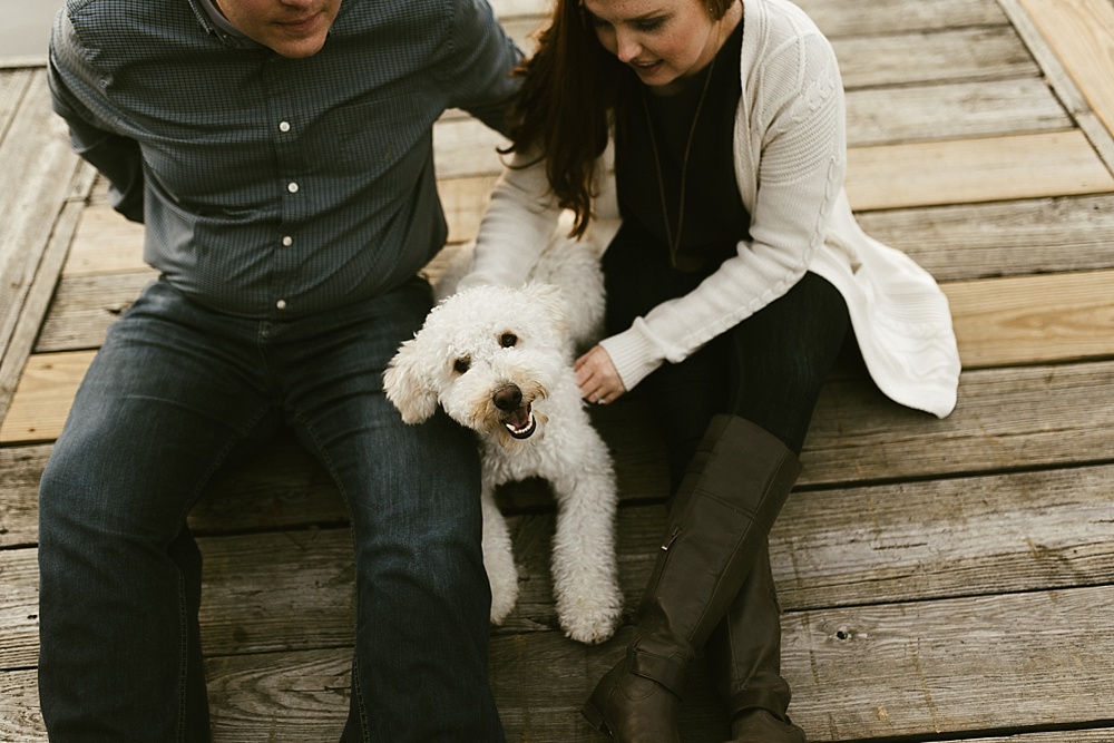 couple playing with dog on pier at chain o'lakes fall engagement session