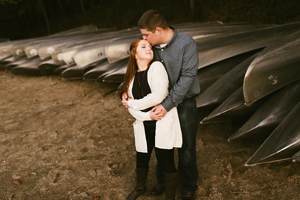 couple hugging next to lake at chain o'lakes fall engagement session