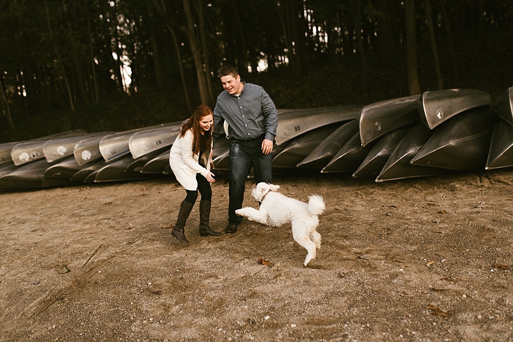 couple playing with dog on beach at chain o'lakes fall engagement session