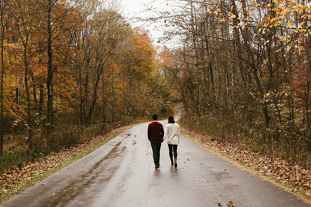 couple holding hands walking at cataract falls fall engagement session