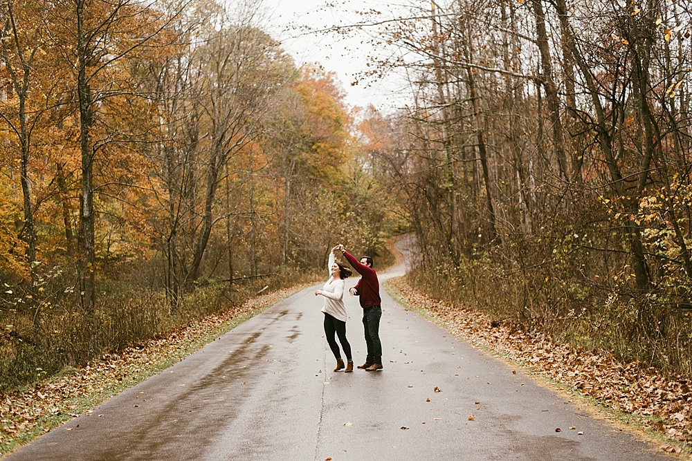 couple twirling in road at cataract falls fall engagement session