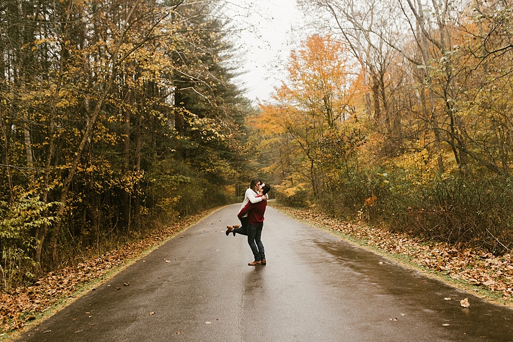 couple twirling in road at cataract falls fall engagement session