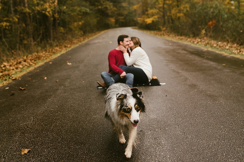 couple kissing with dog at cataract falls fall engagement session