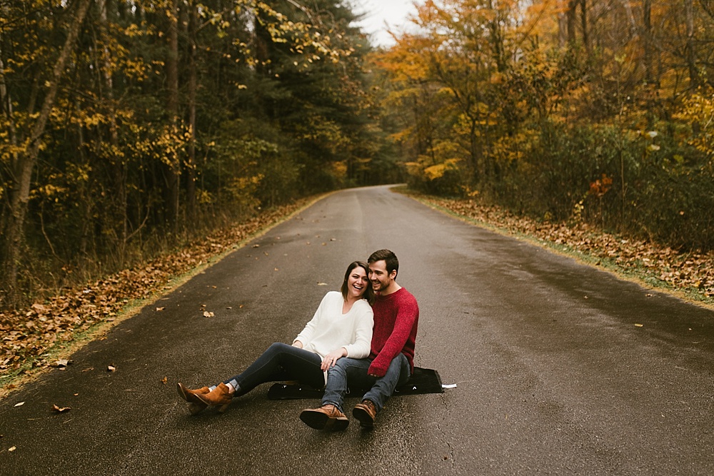 couple sitting in road at cataract falls fall engagement session