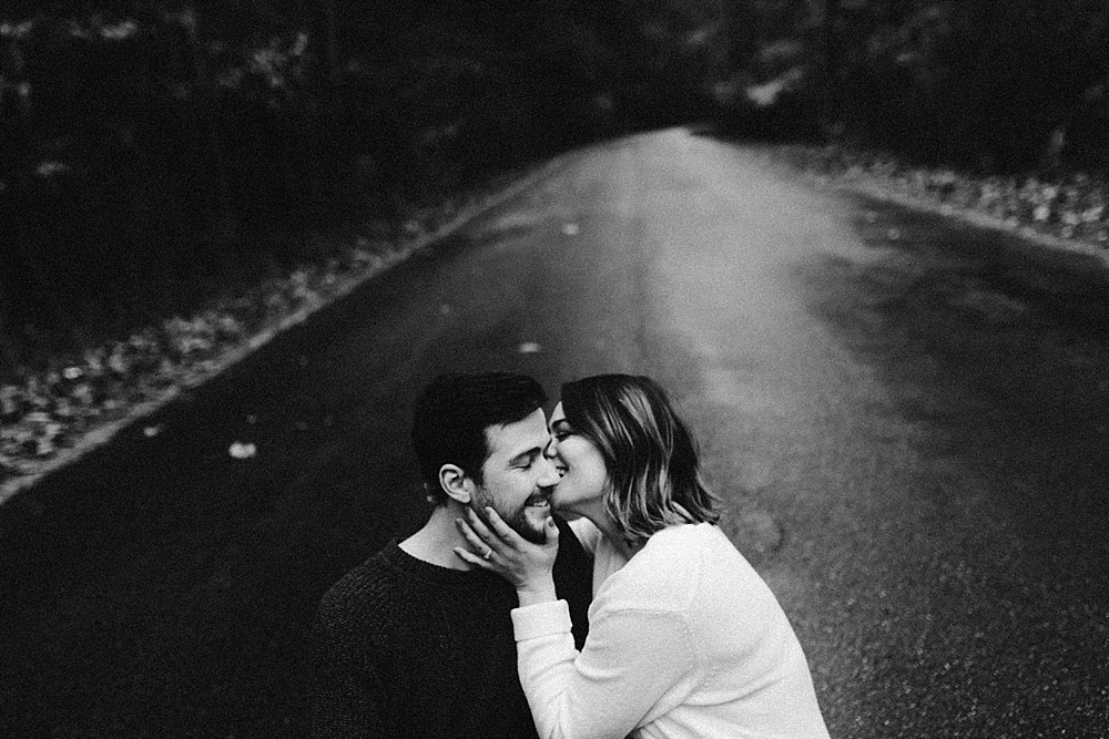 couple sitting laughing on road at cataract falls fall engagement session