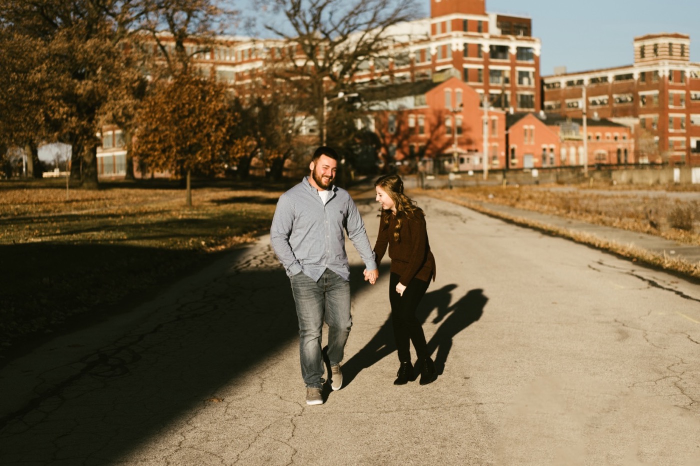 couple holding hands walking through GE campus at downtown fort wayne engagement session
