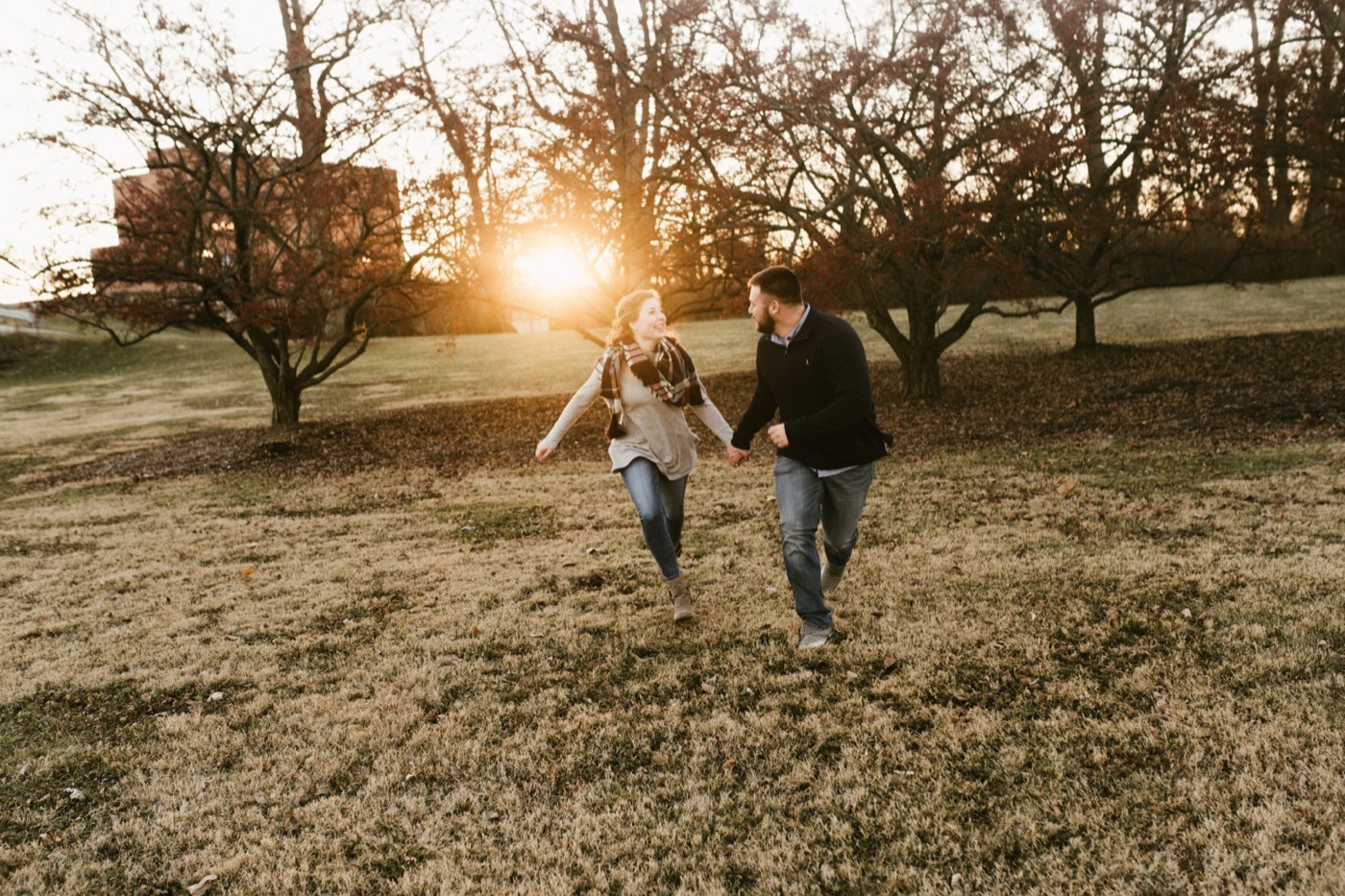 couple holding hands and running at golden hour at downtown fort wayne engagement session