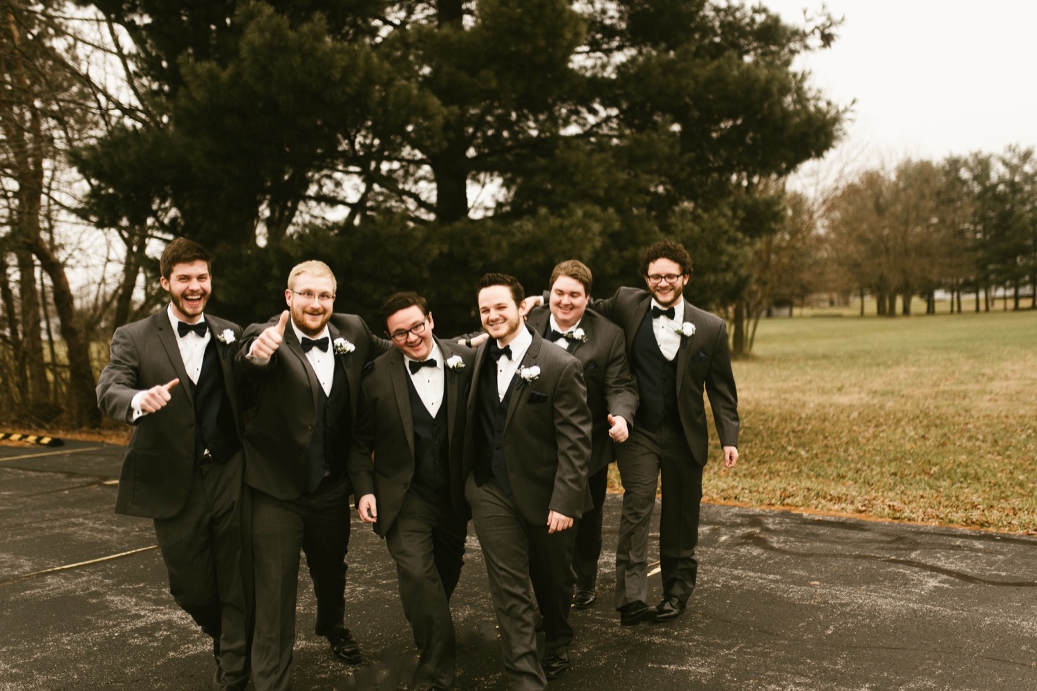 groom and groomsmen walking and laughing at fort wayne winter wedding