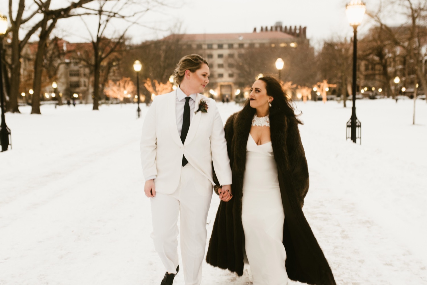 Chicago brides holding hands walking through the snow.