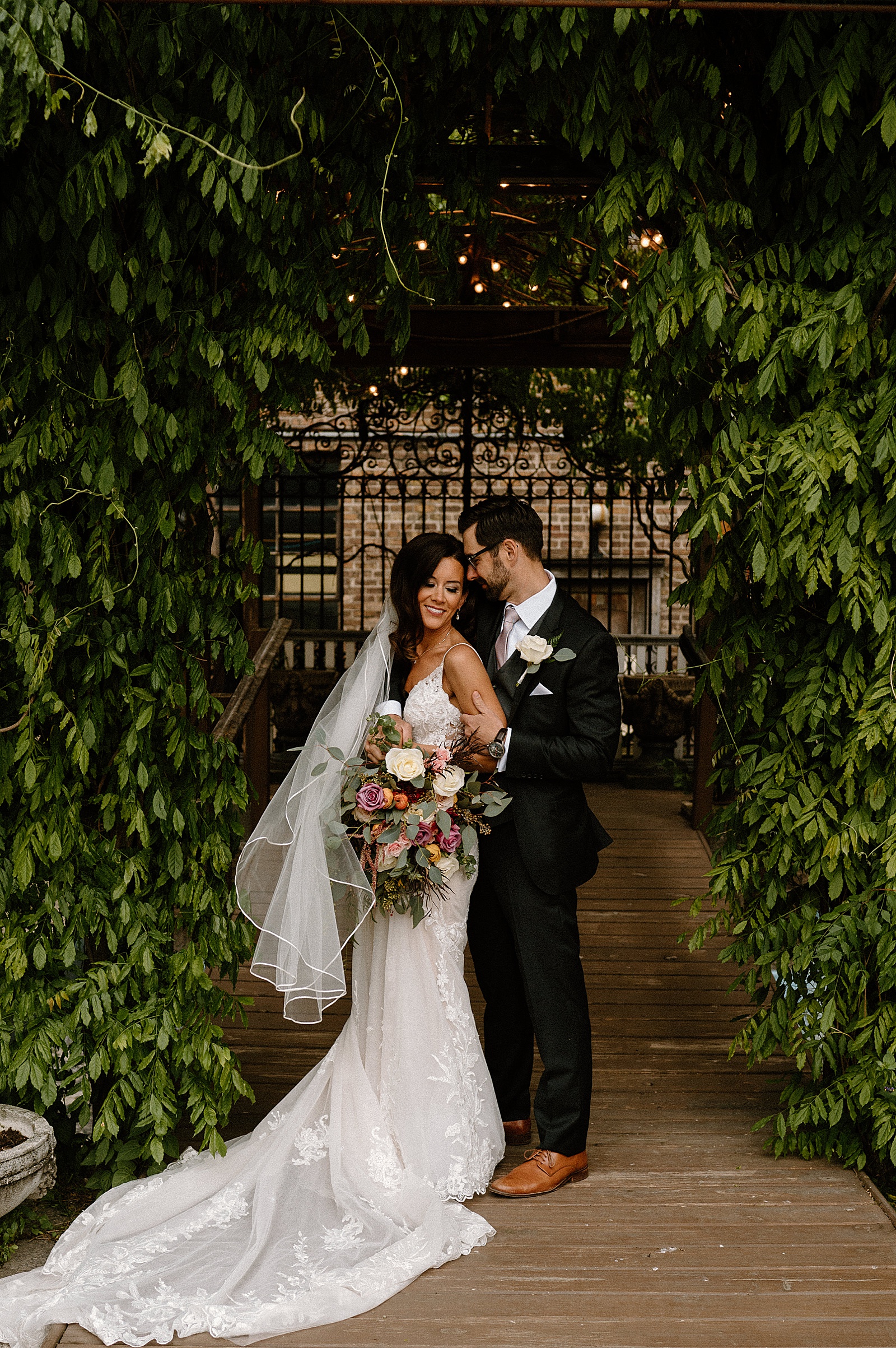 Wedding couple embracing under greenery for their Chicago special day 