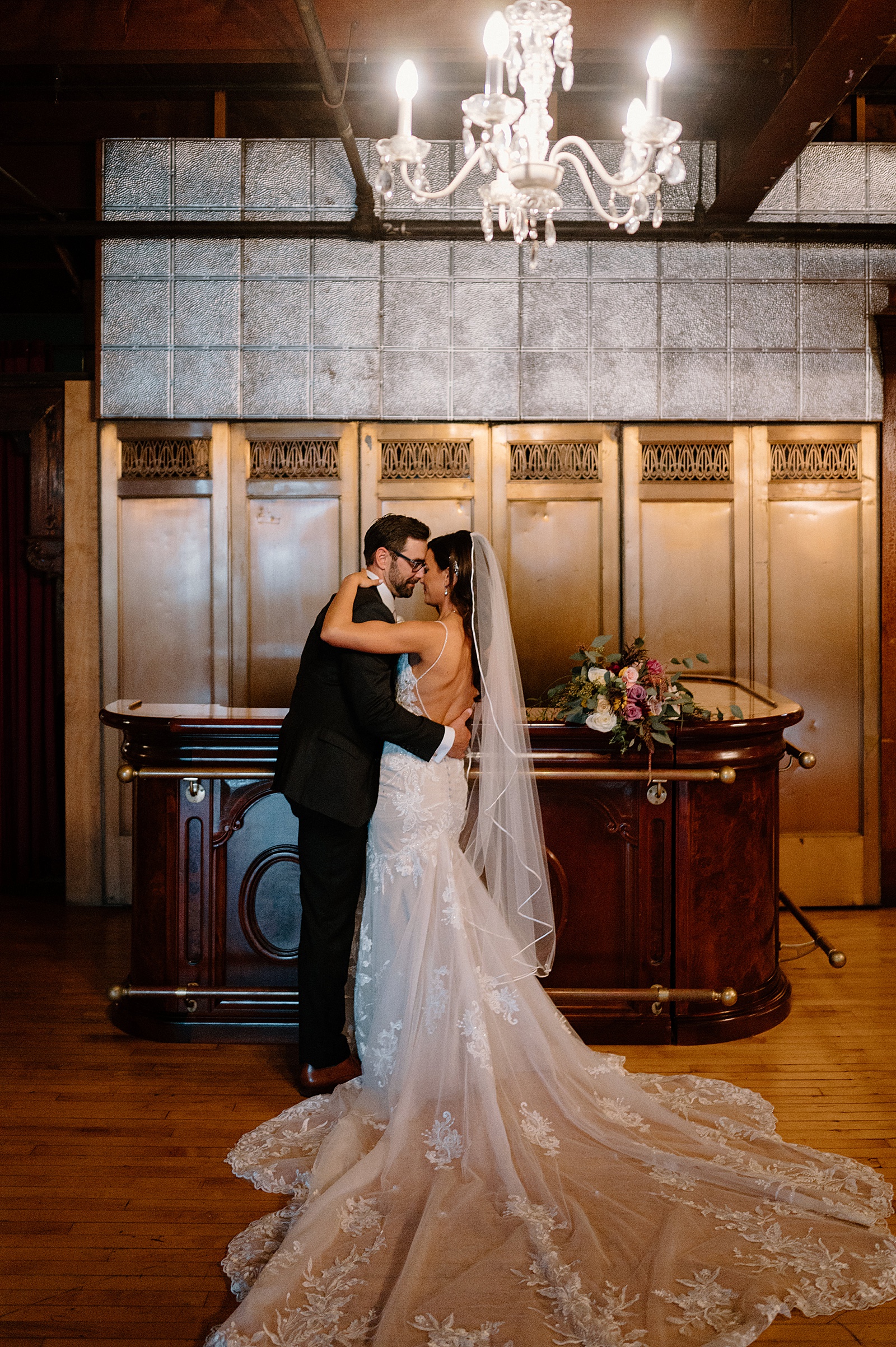Bride and groom embracing next to a vintage bar at Salvage One