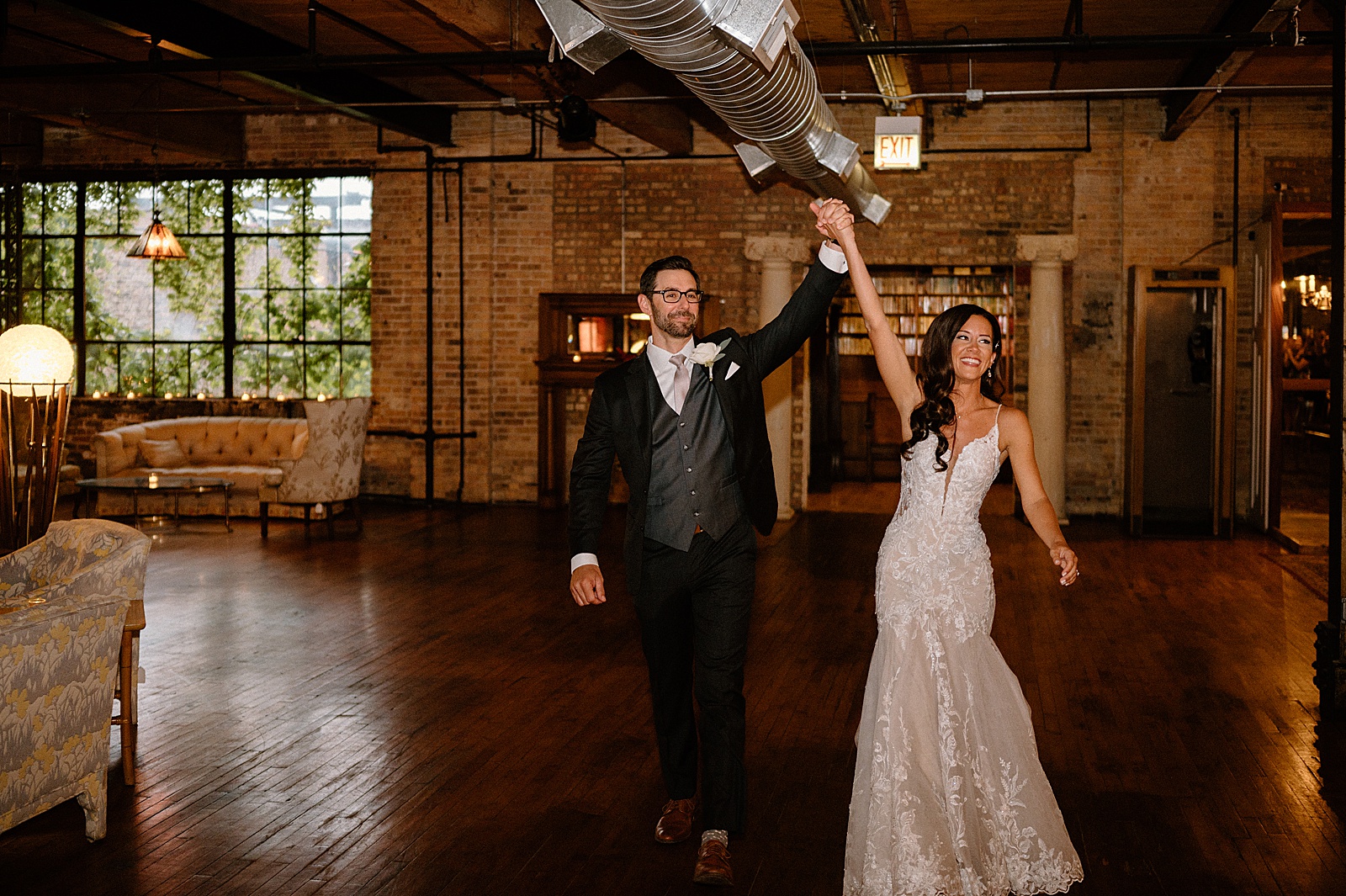 Newlyweds entering a wedding reception with their hands in the air