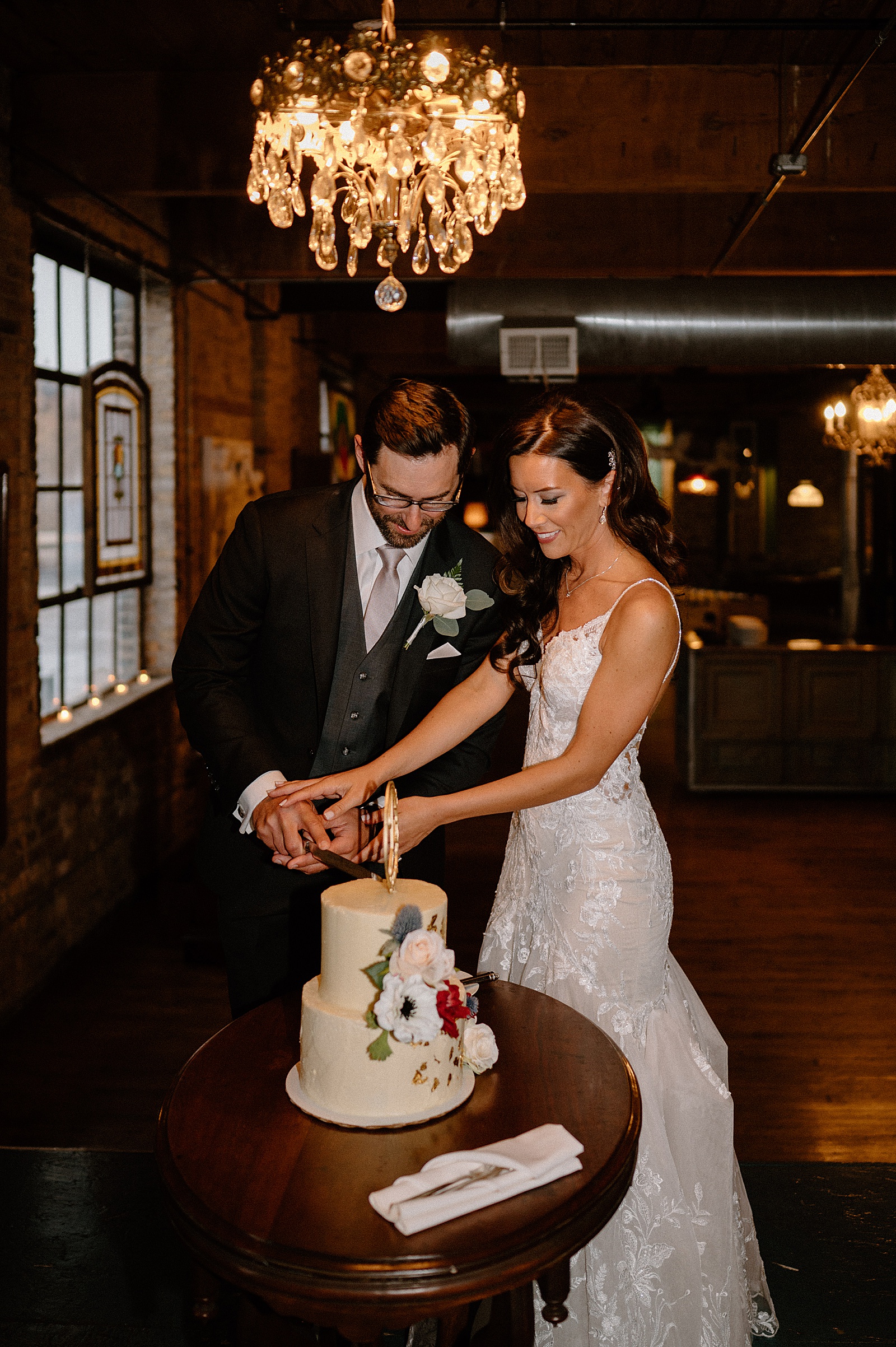 Newlyweds at their wedding reception cutting a cake 