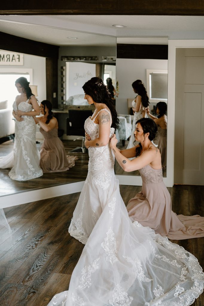 Bride getting her dress zipped in front of a mirror in the bridal suite at Union 12.