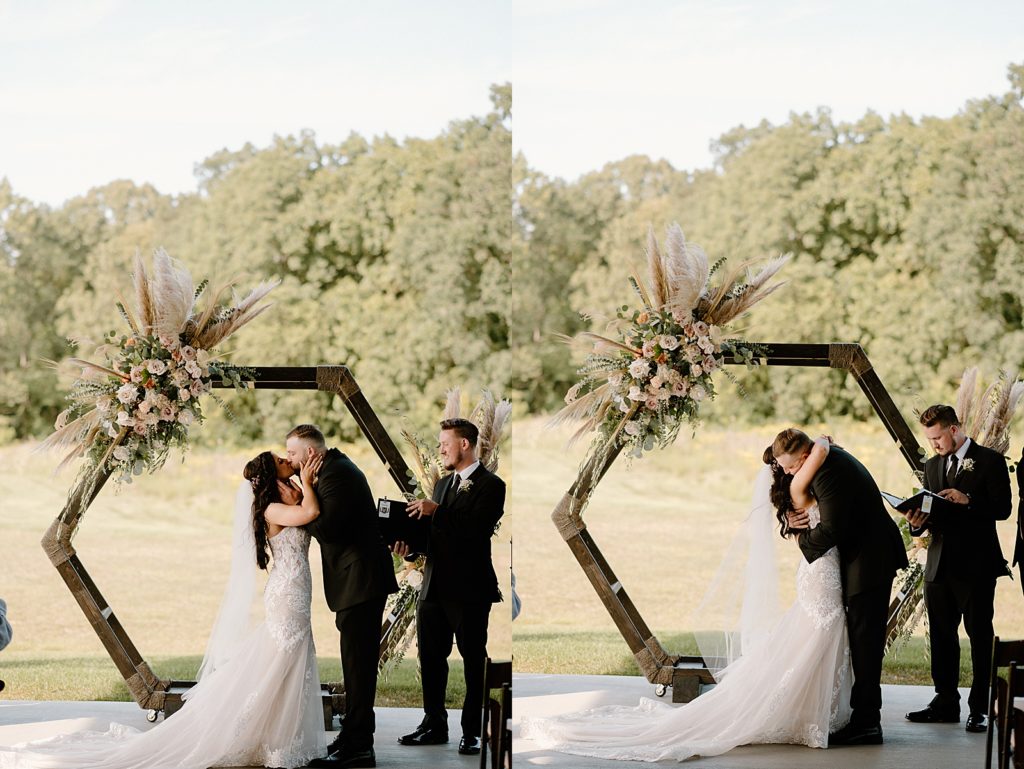 Newlyweds sharing a kiss under a hexagon alter with boho flowers. 