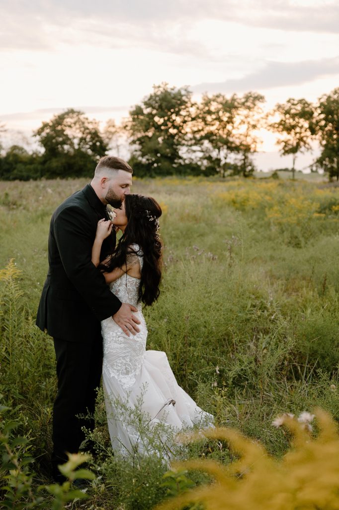 Groom kissing bride's forehead in a field during golden hour by Fort Wayne photographer, Indigo Lace. 