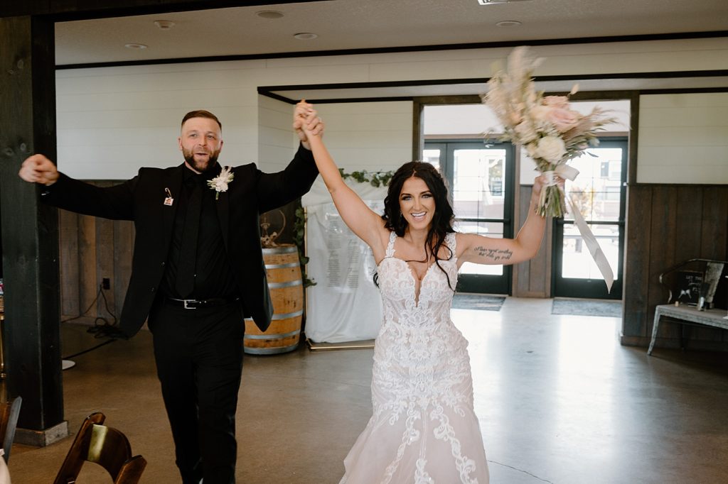 Bride and groom walking into the reception at Union 12 with their hands in the air. 
