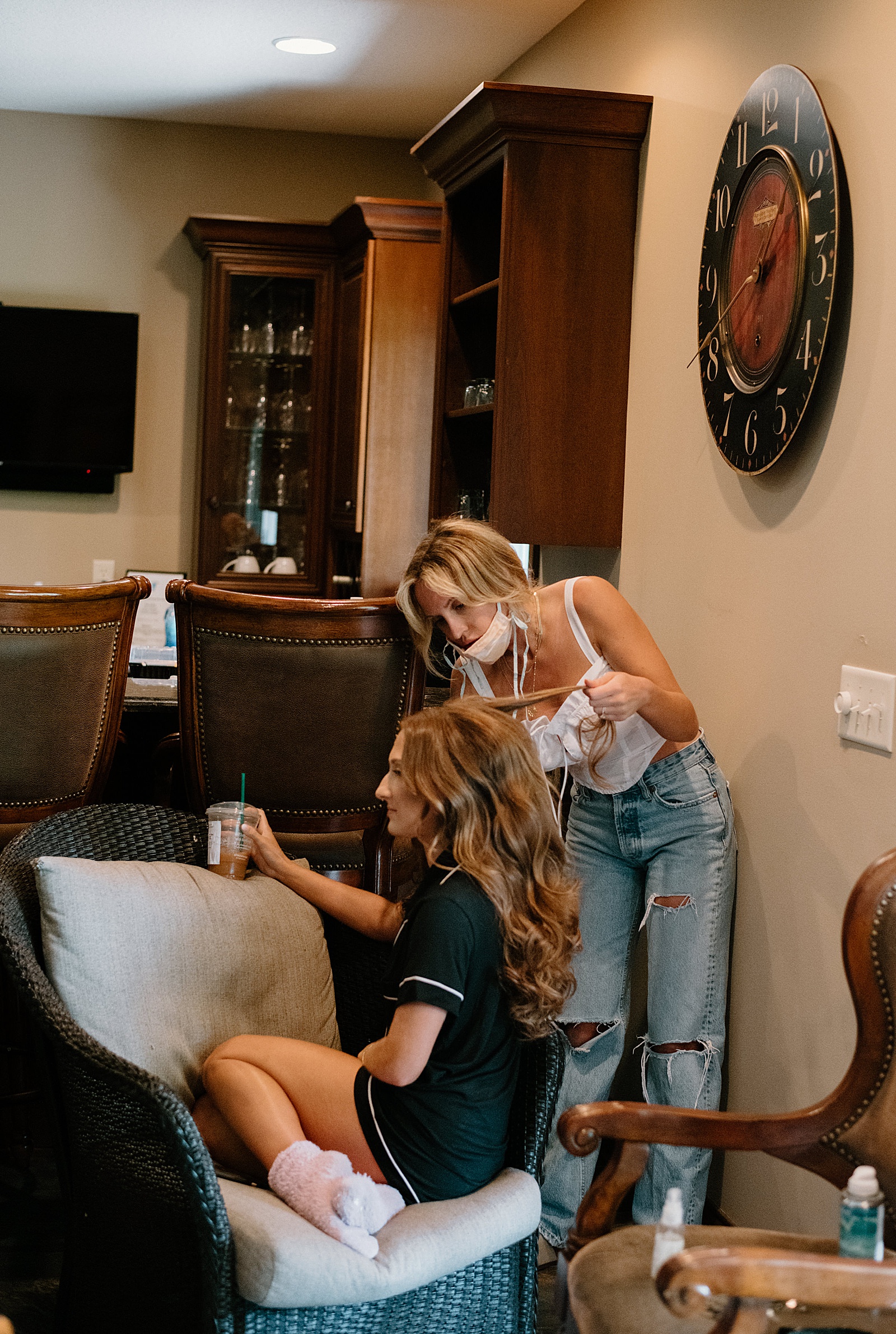 Bride getting her hair fixed by a woman in a white shirt wearing a mask. 