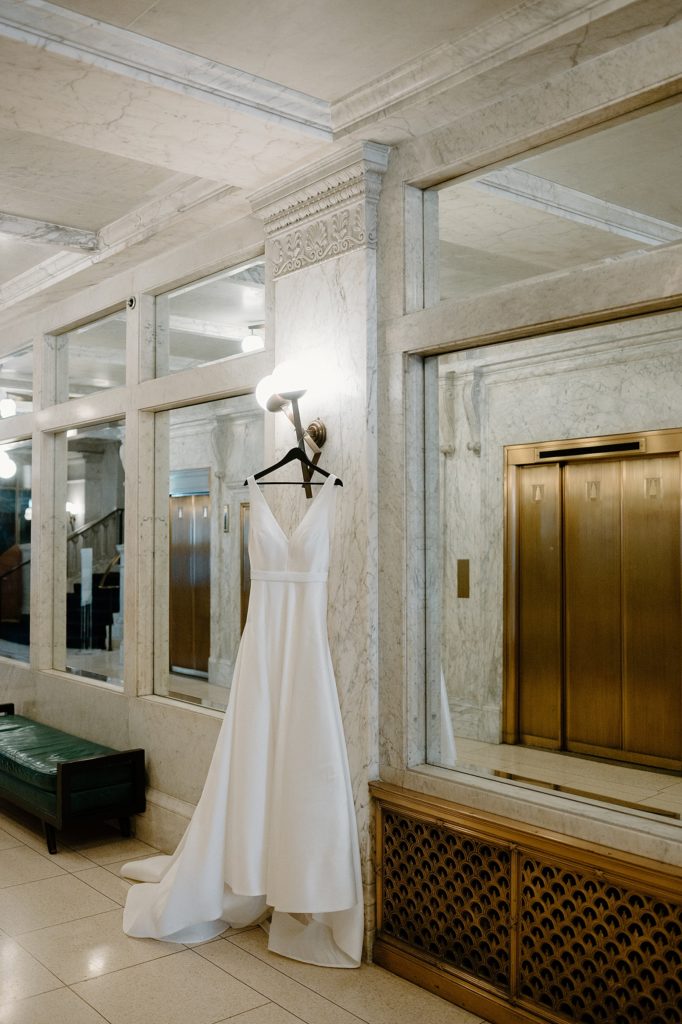 Bridal gown hung on ornate elevator column for boho wedding in Illinois 