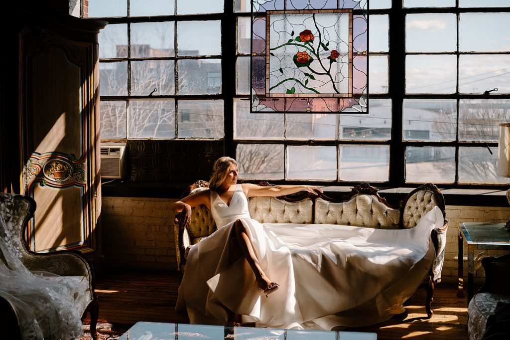 Bride on a couch in the sunlight at a boho vintage wedding venue in Illinois 