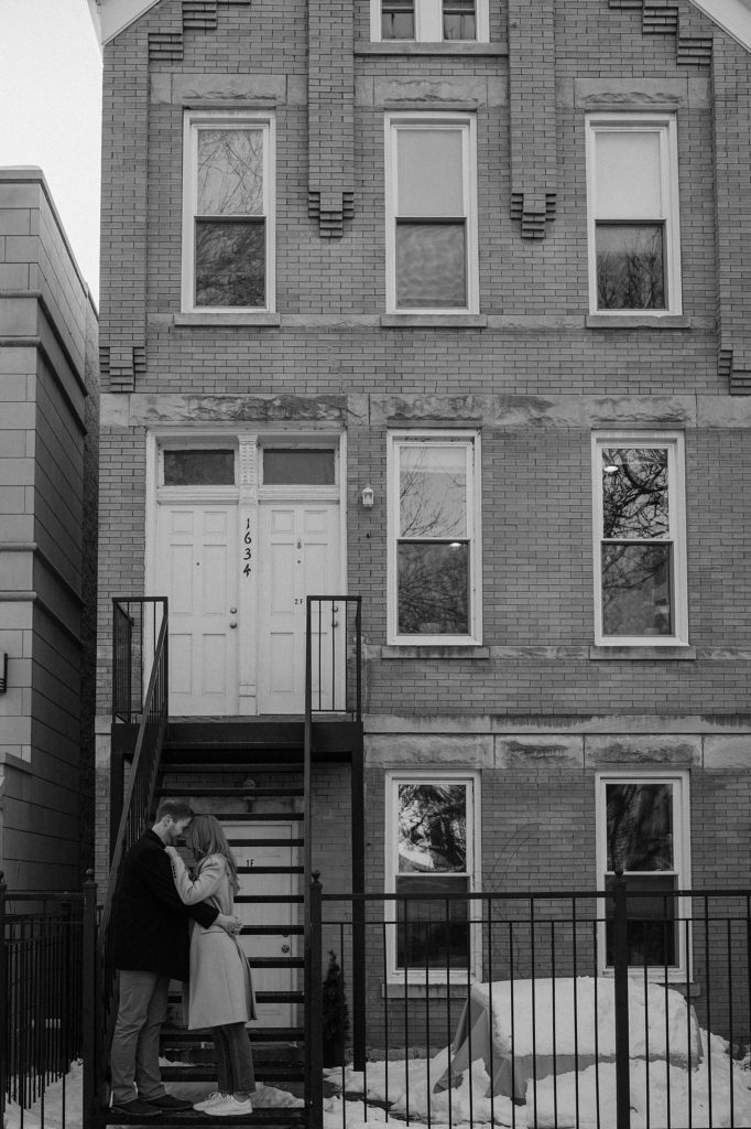 Engaged couple kissing on doorstep  by Chicago wedding photographer Indigo Lace 