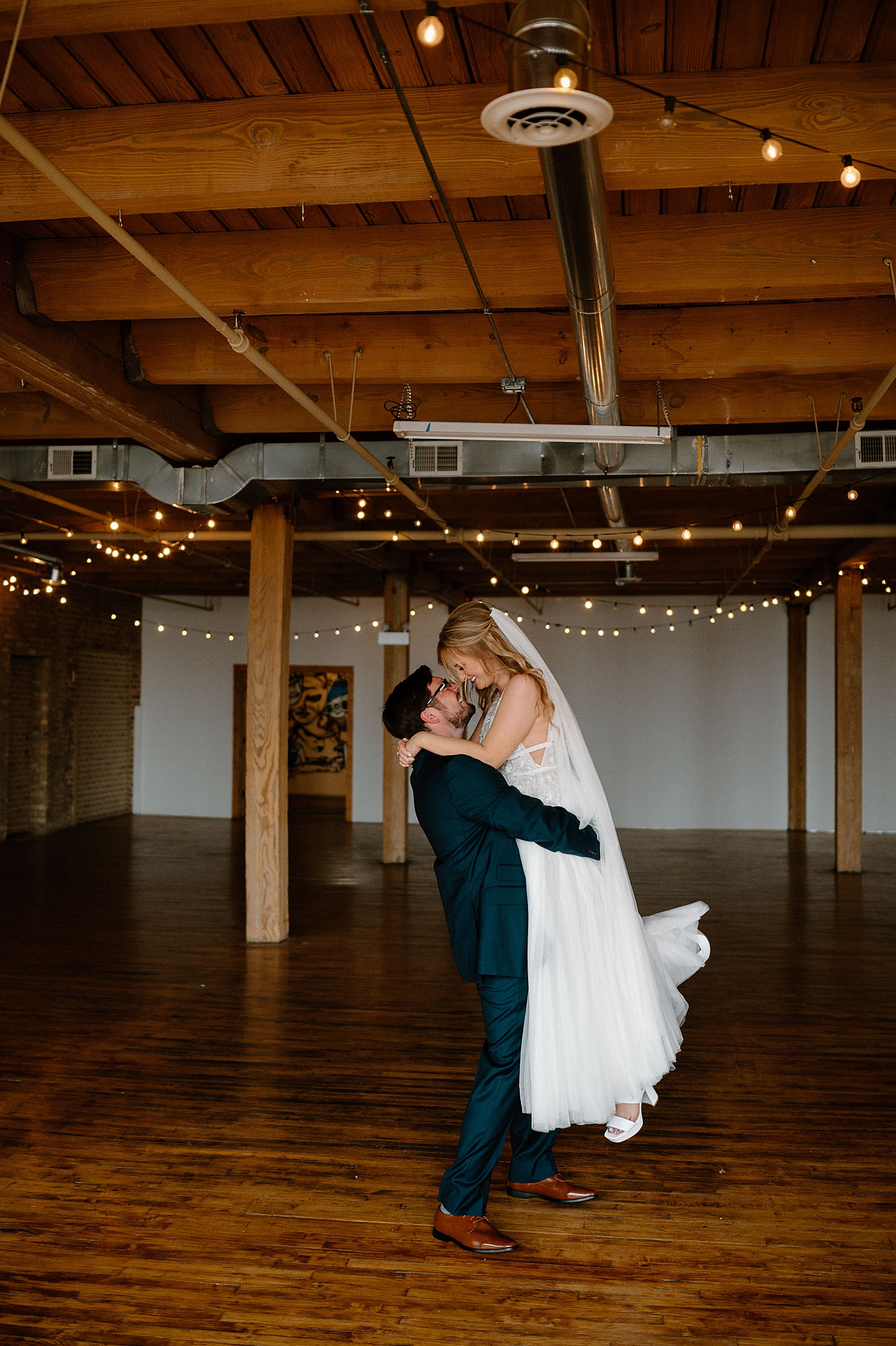 Groom lifts up bride in warehouse after saying I Do 