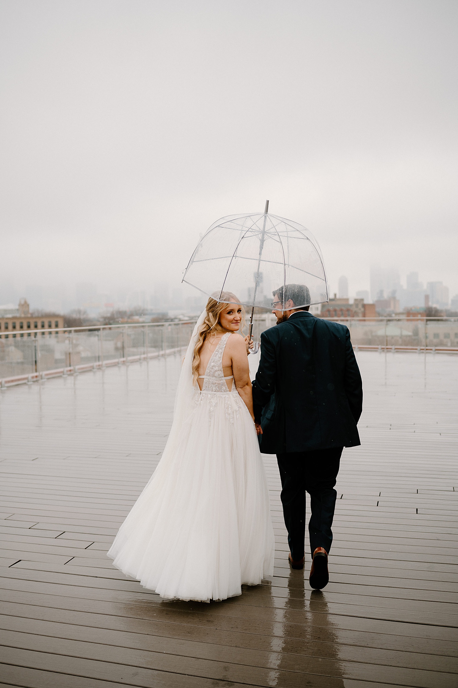 Newlyweds walking outside in the rain  by Midwest wedding photographer Indigo Lace