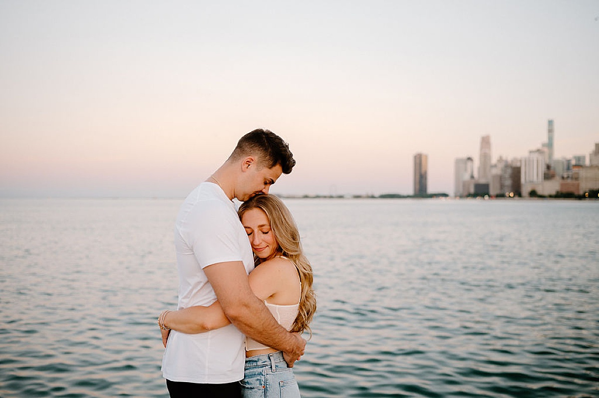 man kisses woman's head during sweet Grant Park and Chicago Skyline Engagement Session