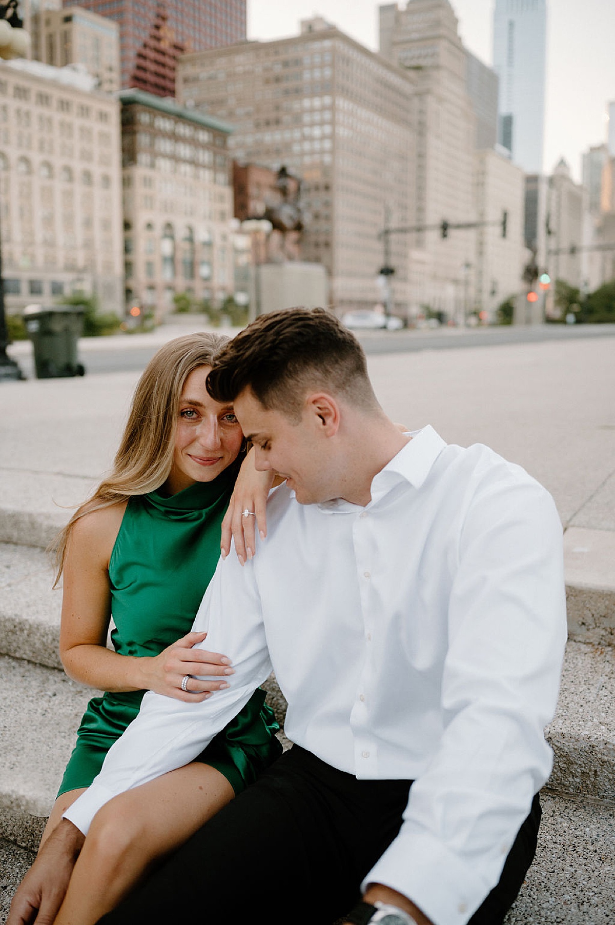 woman in green cocktail dress poses with fiance on chicago steps in shoot by Indigo Lace Collective